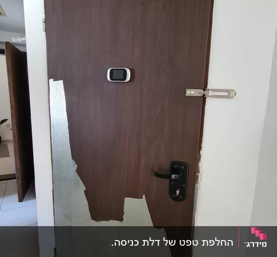 דלת עץ עם ציפוי מתקלף ומנעול שחור